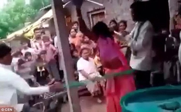 His wife, wearing traditional Indian dress, screamed as he whipped her and tried to move around the pole in a bid to escape the blows