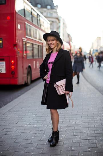 Девушка в юбке плиссе, розоавом топе, черном пальто и шляпе