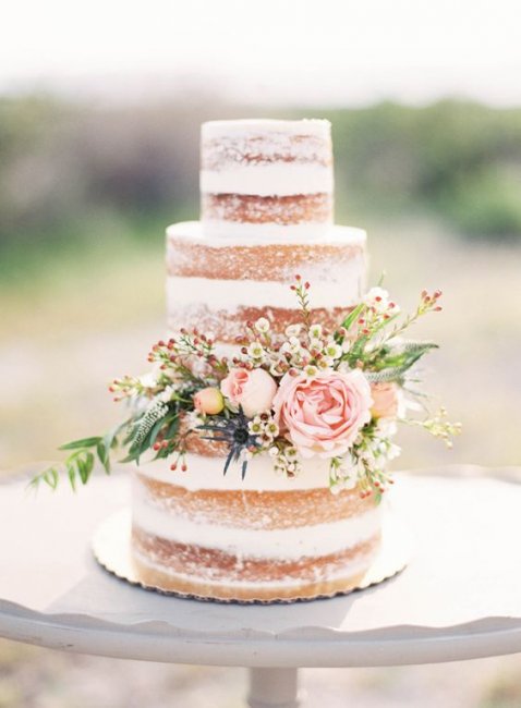 Торт с открытыми коржами, украшенный цветами и зеленью