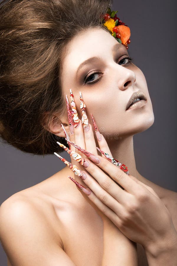 Beautiful girl in autumn image with long nails with bright and unusual make-up. Picture taken in the studio on a gray background stock photo
