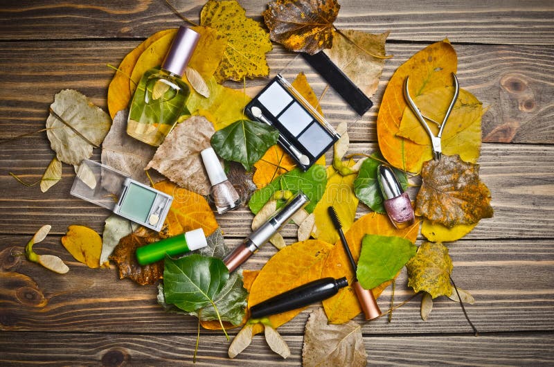 Women& x27;s cosmetics for make-up, objects for care of nails and perfumes lie on a wooden table in yellow autumn leaves. Be always beautiful and well-groomed stock photos